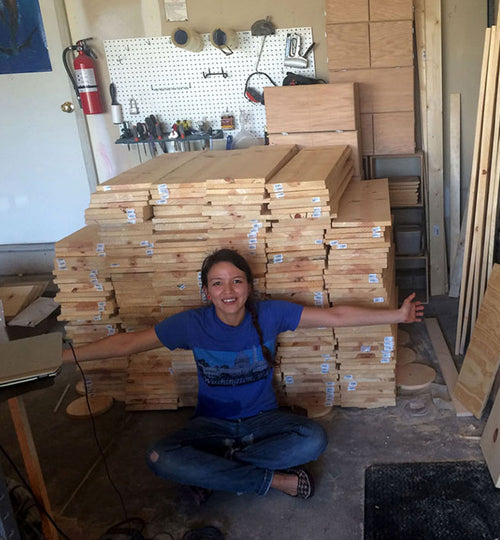 megan sitting with a large stack of wood 