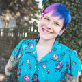 lady with blue dress and tattoos smiling