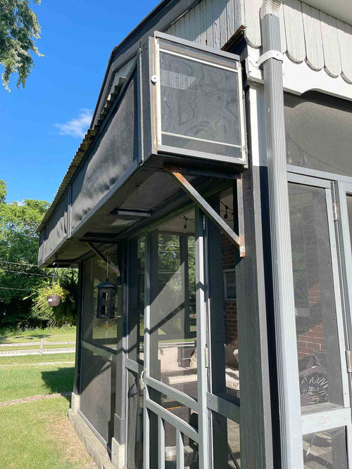 Outdoor elevator attached to a building with a grassy area and trees in the background
