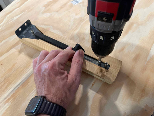 Hand using a drill on a wooden surface