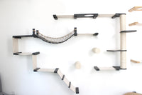 Cat play structure with shelves and a hammock on a white wall